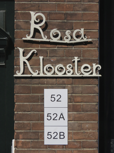 908000 Afbeelding van het siersmeedwerk 'Rosaklooster' en nieuwe huisnummerbordjes op de gevel naast de ingang van het ...